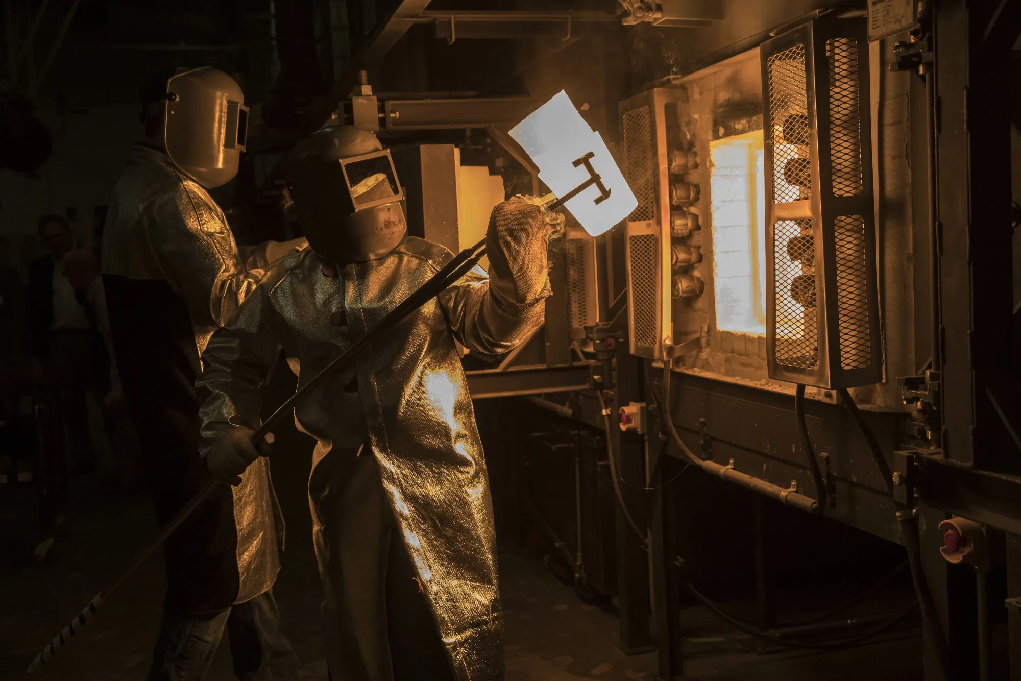 An employee pulls a crucible of molten glass from a furnace at the Corning Inc. facility in Corning, New York.