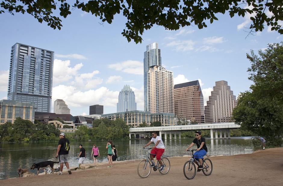 Cyclists pass beneath the downtown skyline on the hike-and-bike trail on Lady Bird Lake in Austin.