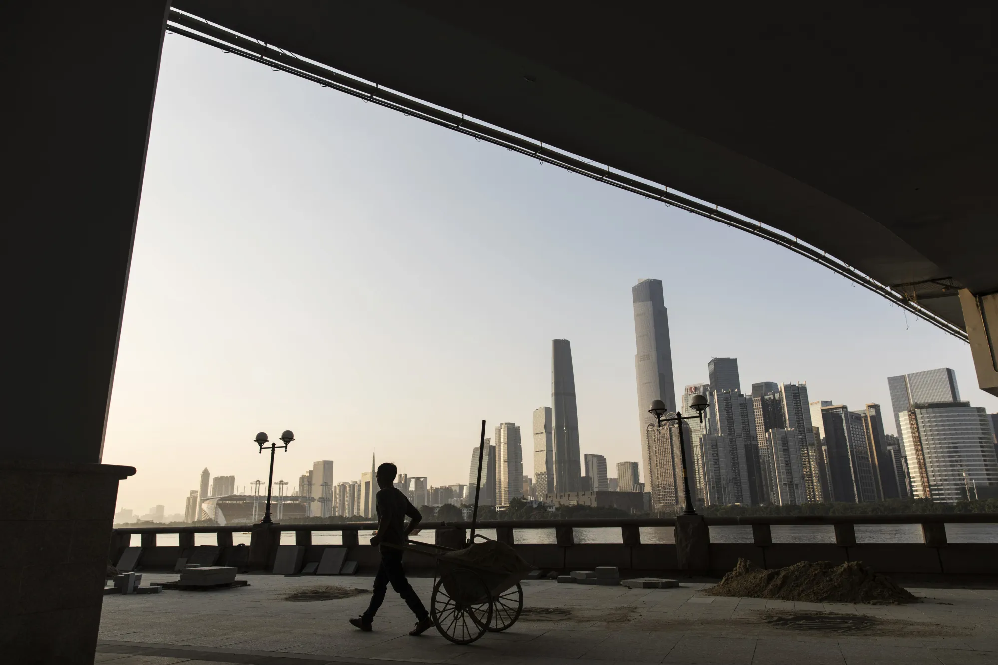 A worker pulls a cart under the Liede Bridge over the Pearl River in Guangzhou, China.