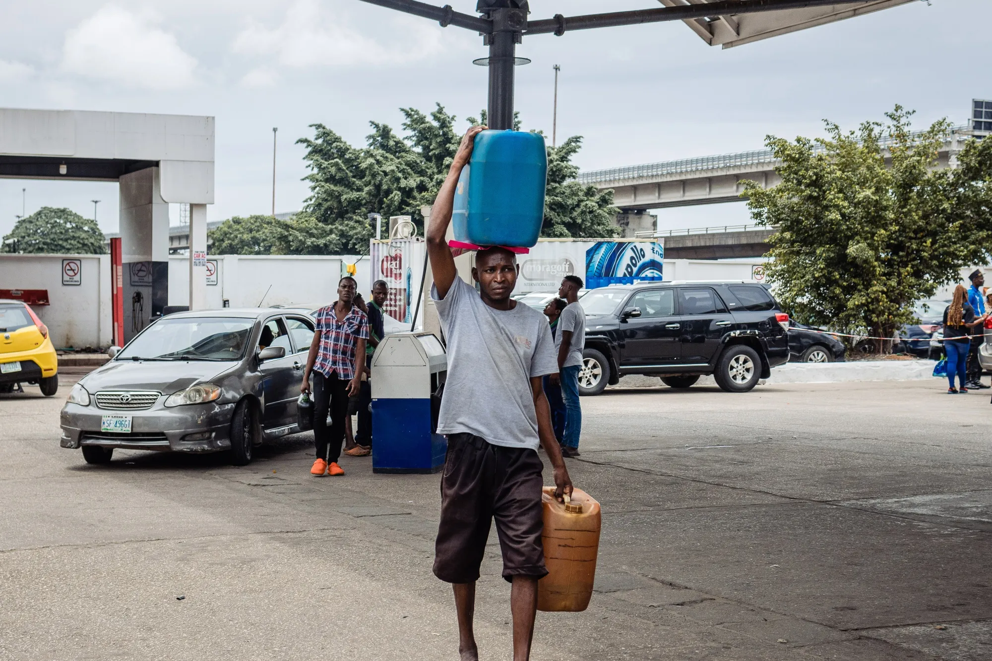 A customer carries containers of fuel from a gas station in Lagos, Nigeria.