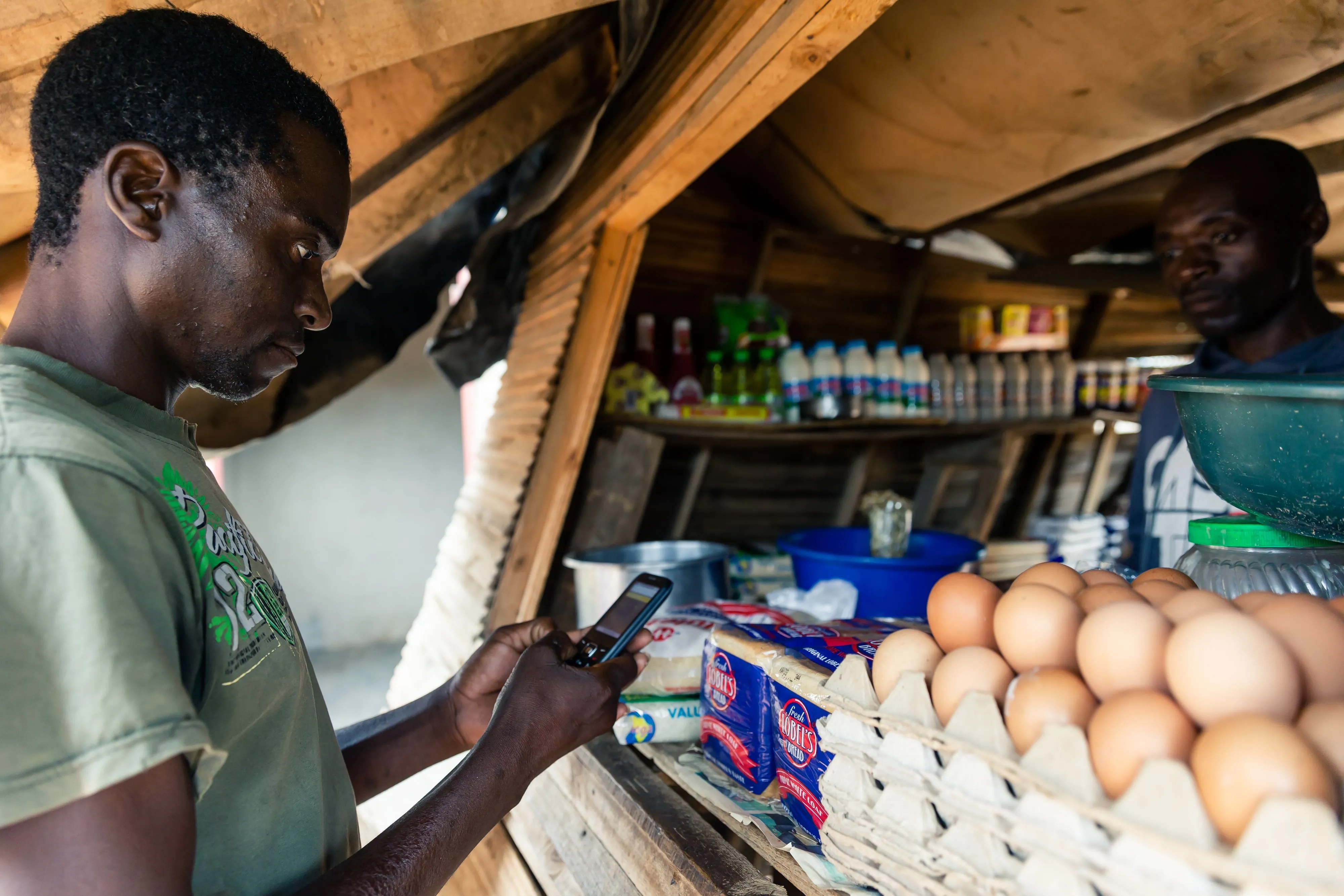 A customer&nbsp;makes a payment from his mobile phone for basic food items&nbsp;on the outskirts of Harare.