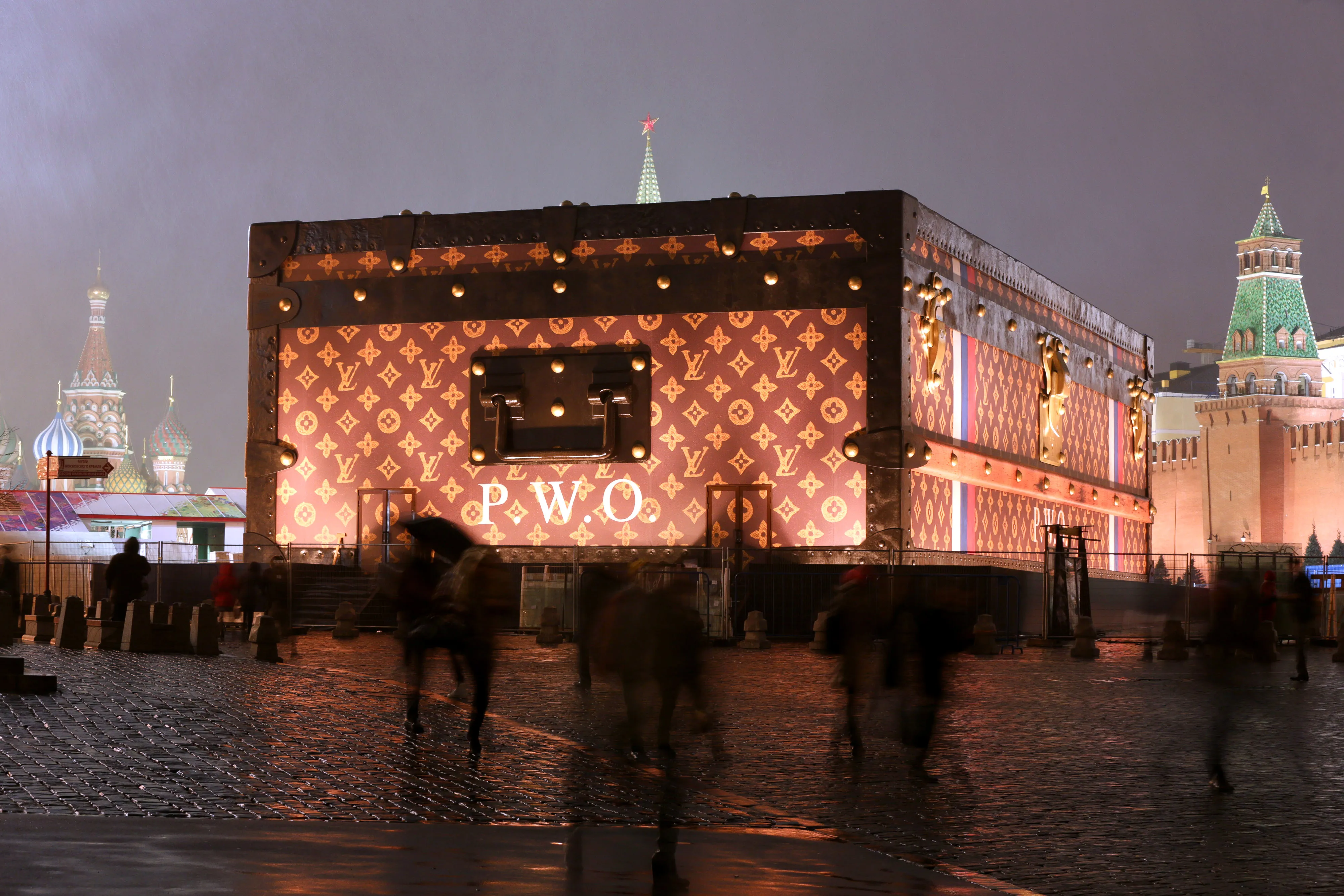 Pedestrians pass a promotional exhibit -- a large wooden chest bigger than Lenin's tomb -- for Louis Vuitton, in Red Square, Moscow, in November 2013. Photographer: Andrey Rudakov/Bloomberg