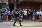 A riot police officer points a tear gas rifle towards demonstrators in Hong Kong, on July 1.