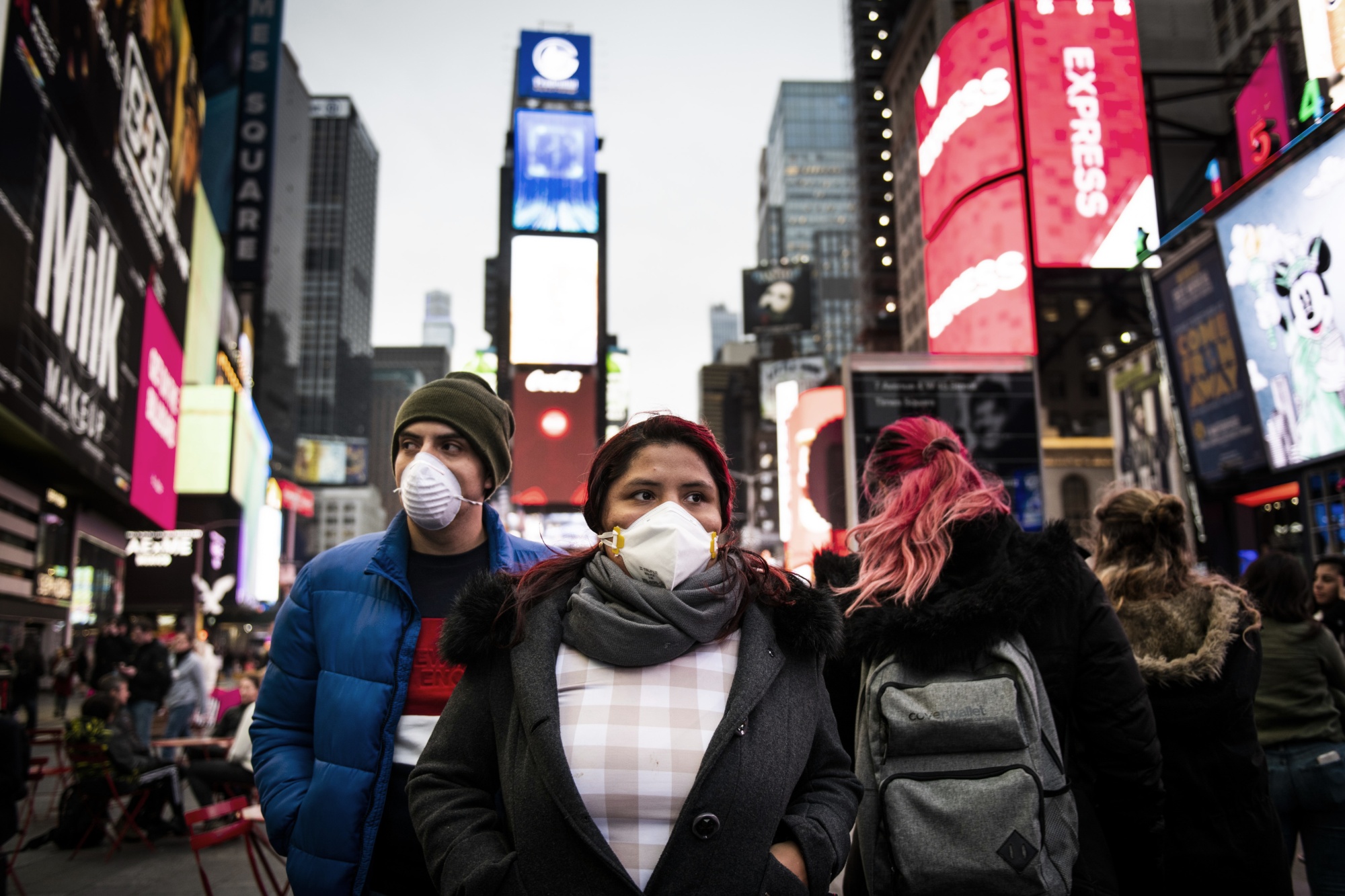 Pedestrians wearing protective masks walk through the Times Square in New York, March 12.