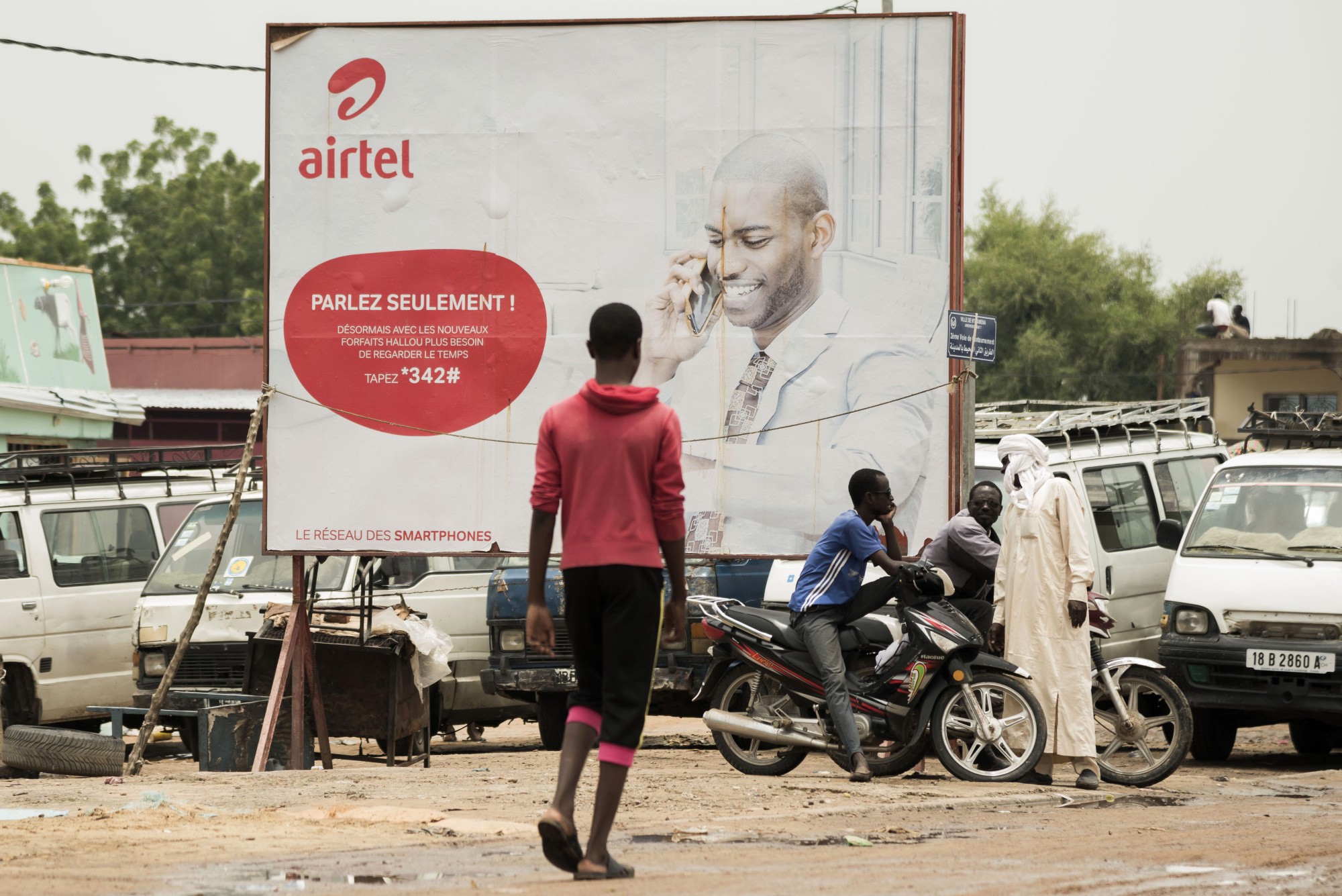 Pedestrians stand beside an advertisement for Bharti Airtel in N'Djamena, Chad, on&nbsp;Aug. 15, 2017.&nbsp;