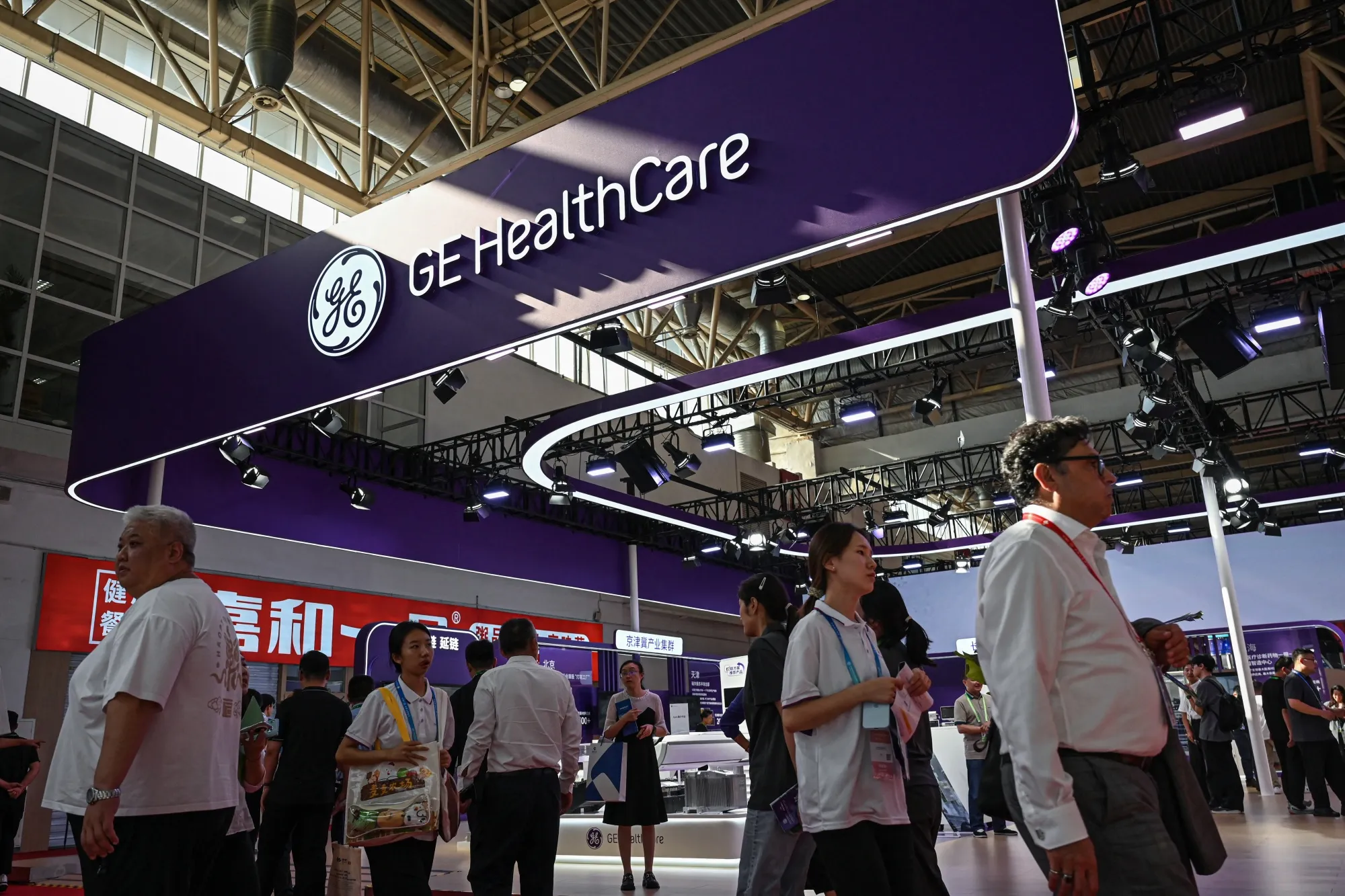 People walk past a GE HealthCare booth during the 2025&nbsp;China International Supply Chain Expo in Beijing on July 16.