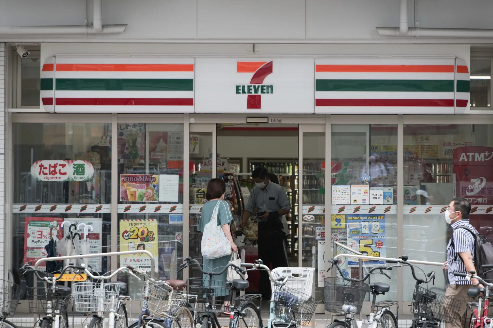 Customers inside a 7-Eleven convenience store, operated by Seven &amp; i Holdings Co., in Kobe, Japan.