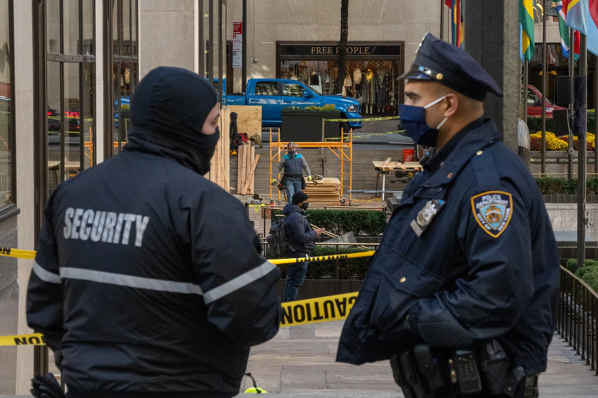 A security guard and a police officer chat as workers board up windows at Rockefeller Center in anticipation of unrest related to the presidential election in New York City on Nov. 2020.