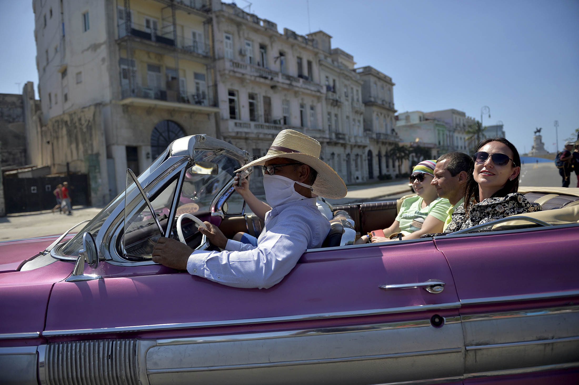 A private taxi driver wears a protective face mask while driving tourists around Havana.