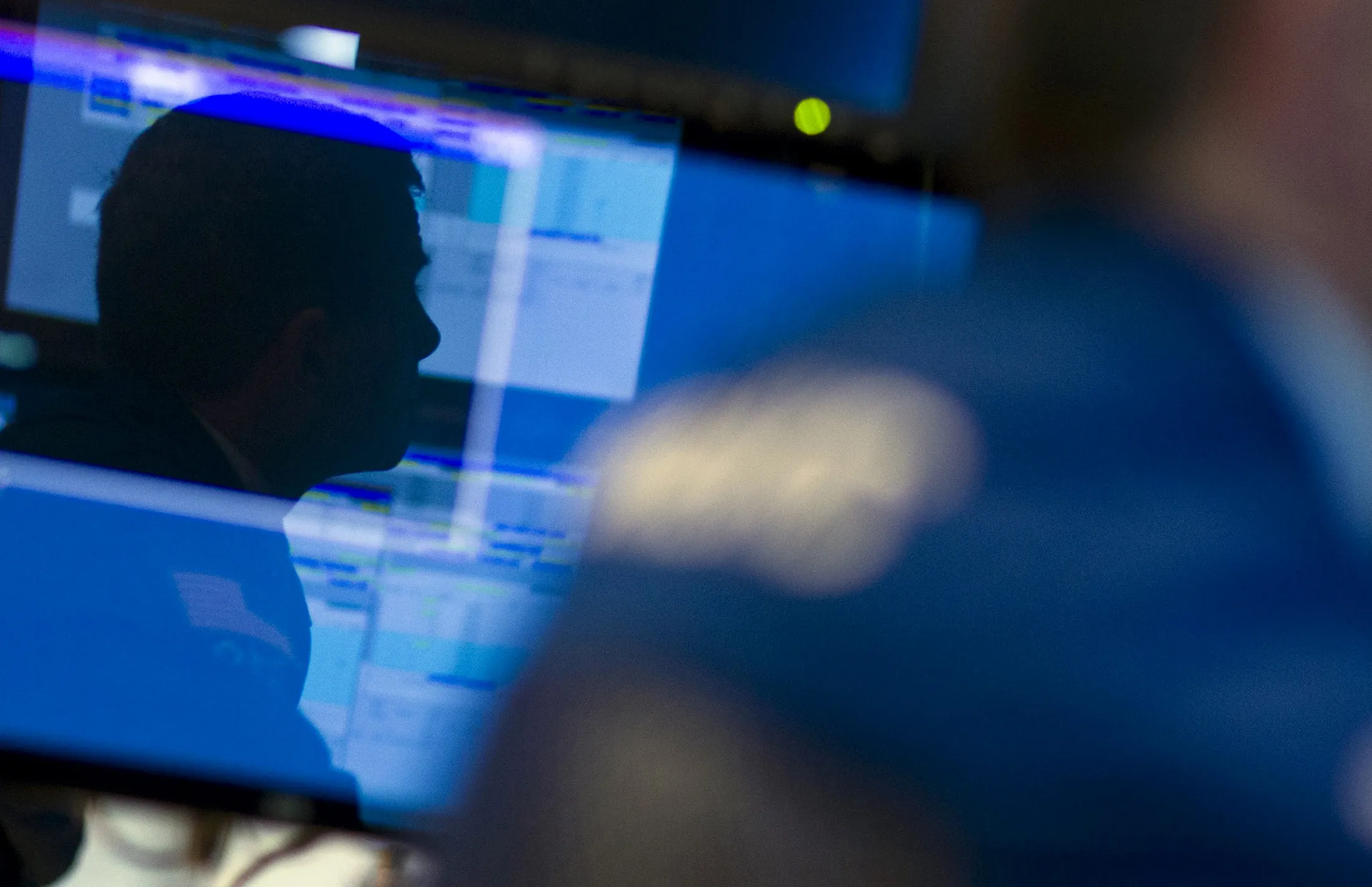 A trader is reflected in a monitor as he works on the floor of the New York Stock Exchange.
