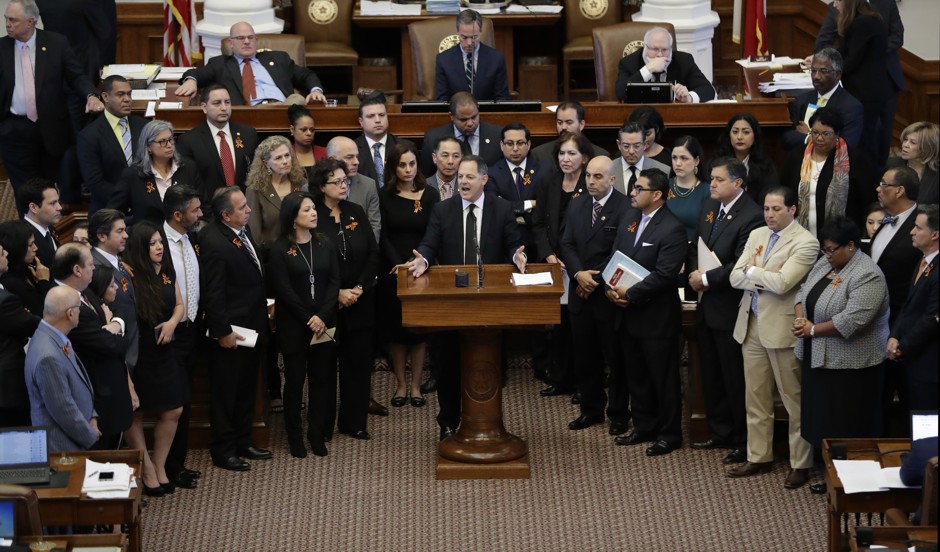 Texas Rep. Rafael Anchia, D-Dallas, at podium, is surrounded by fellow lawmakers as he speaks against an anti-&quot;sanctuary cities&quot; bill.