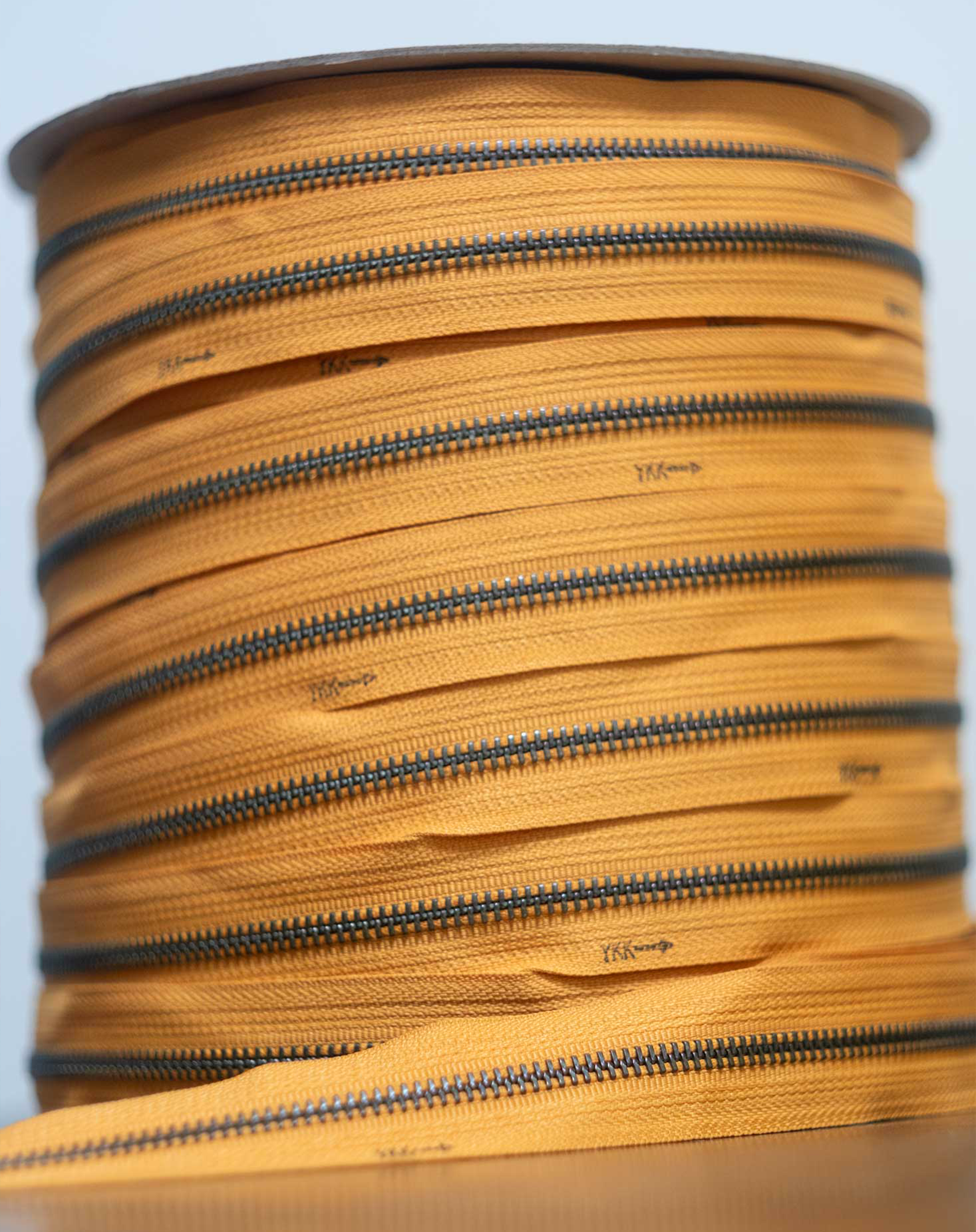 A continuous zipper spool in mustard yellow.