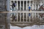 Pedestrians and cyclists pass the U.S. Treasury building in Washington, D.C., U.S., on Sunday, April 10, 2022.