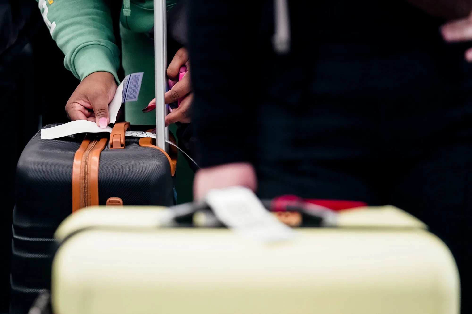 A traveler puts a tag on their luggage.
