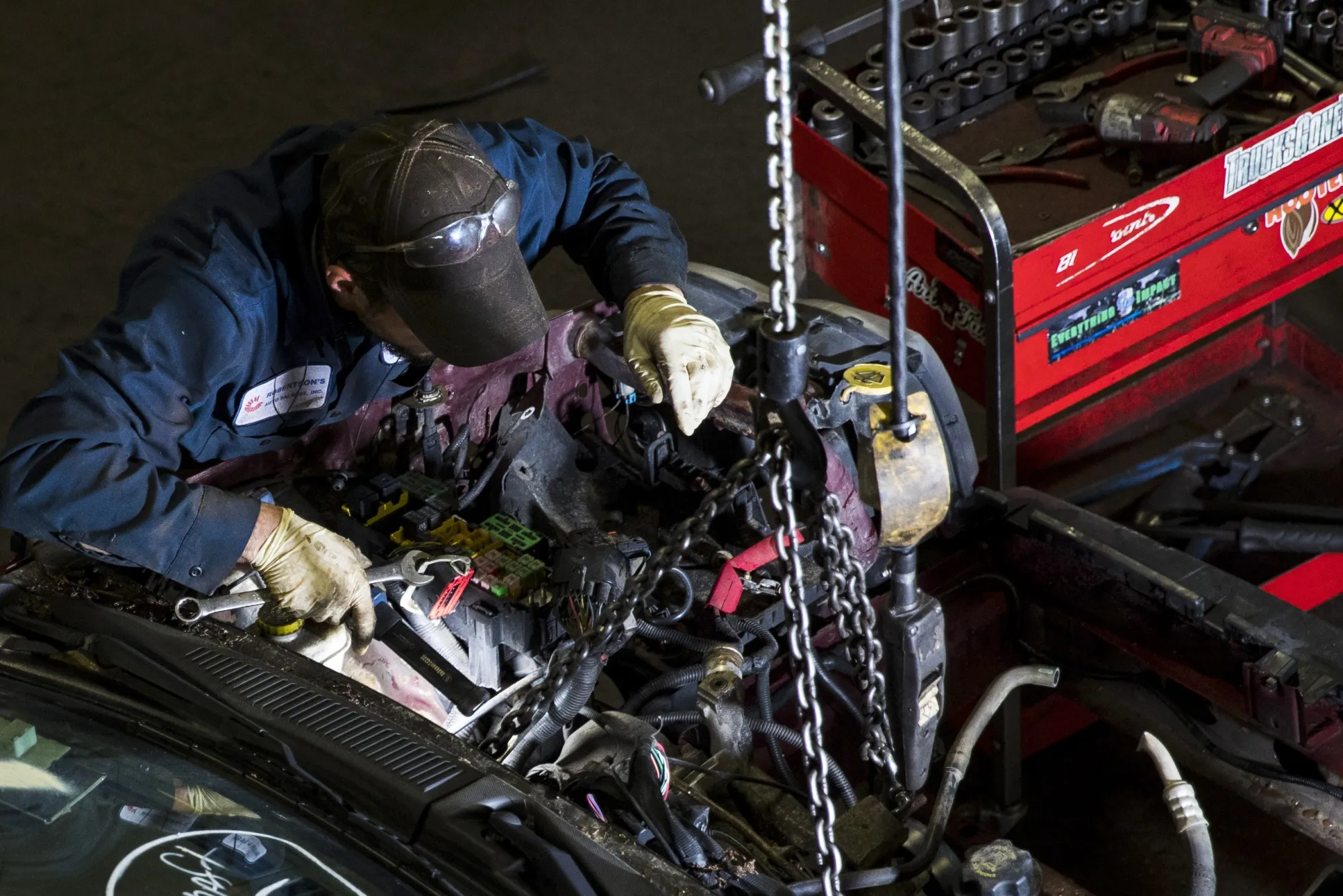 A worker disassembles a car at an auto shop in Wareham, Massachusetts.
