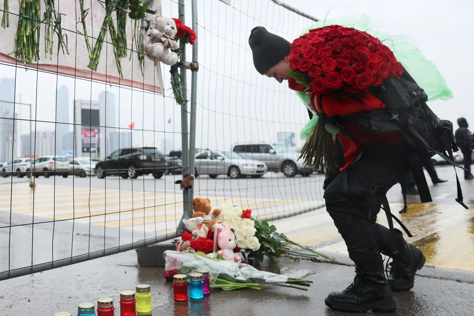 A woman lays flowers at a makeshift memorial in front of the Crocus City Hall.