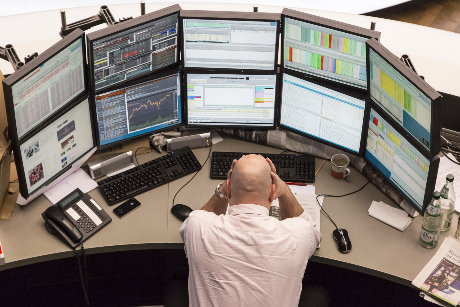 A financial trader reacts as he monitors data on computer screens at the Frankfurt Stock Exchange.