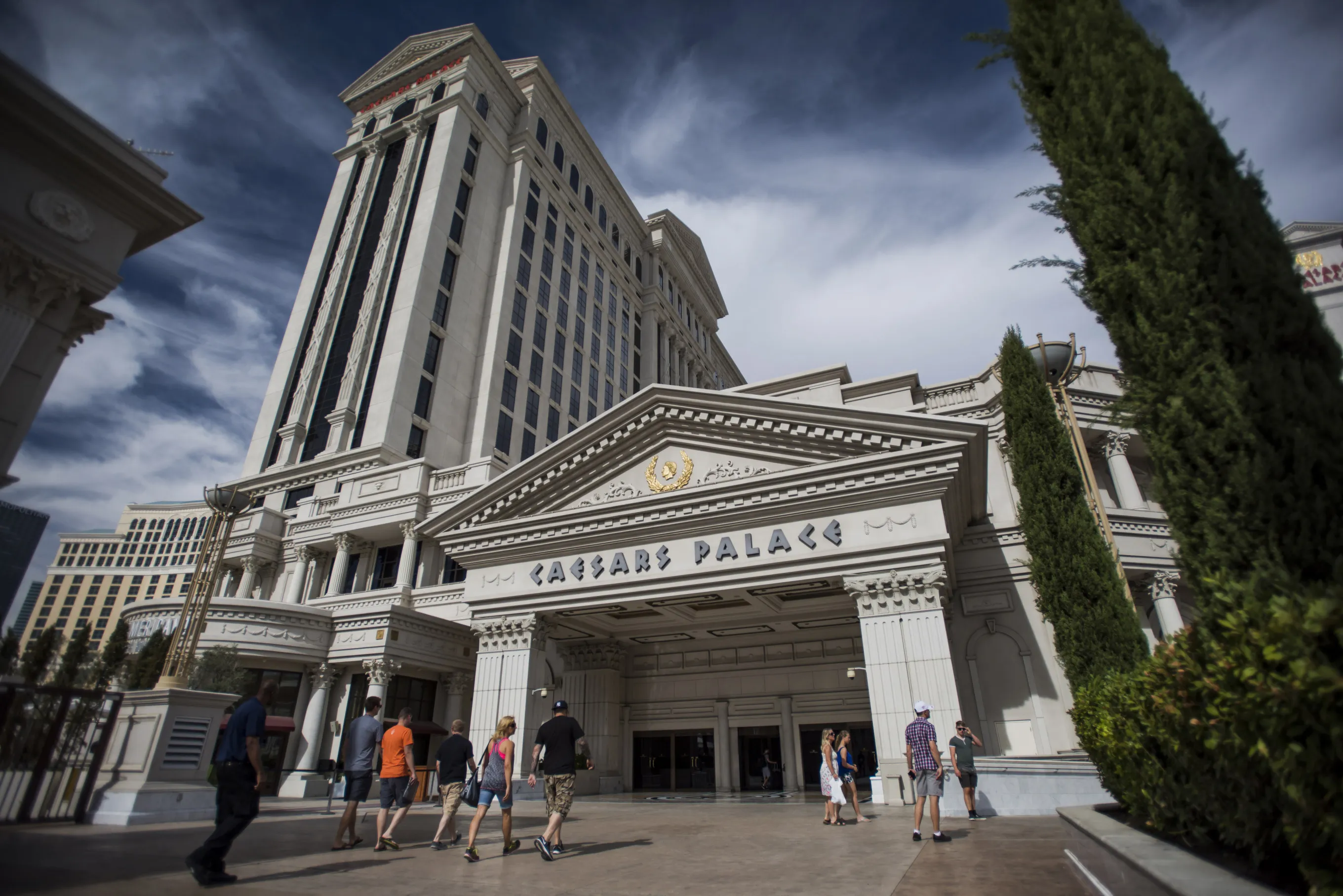 Tourists walk towards the entrance to the Caesars Entertainment Corp.'s Caesars Palace hotel in Las Vegas, Nevada.
