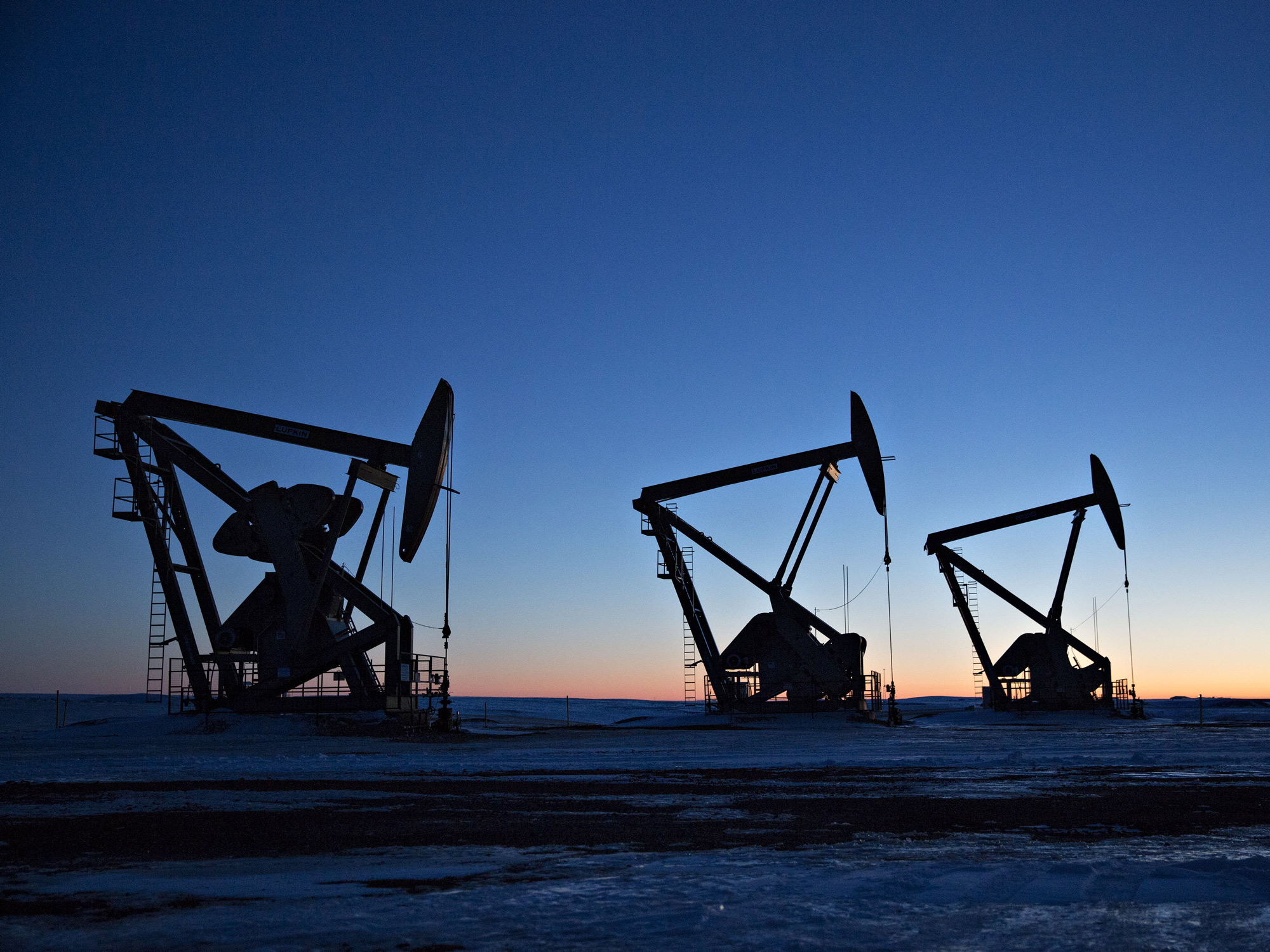 The silhouettes of pumpjacks are seen above oil wells in the Bakken Formation near Dickinson, North Dakota.