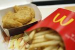 A box of chicken nuggets, left, sits beside a portion of french fries in this arranged photograph at a McDonald's restaurant.