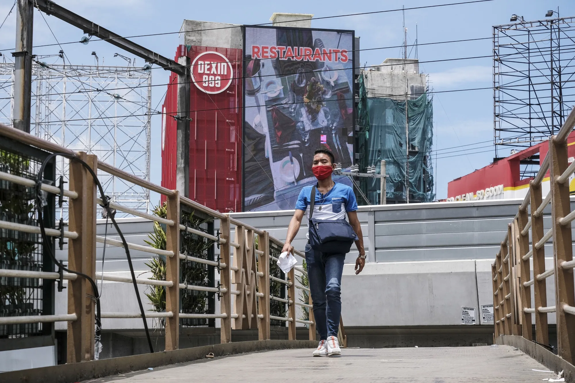 A pedestrian wears a protective face mask while walking across an overpass in Pasay City, Metro Manila, the Philippines, on&nbsp;June 16.