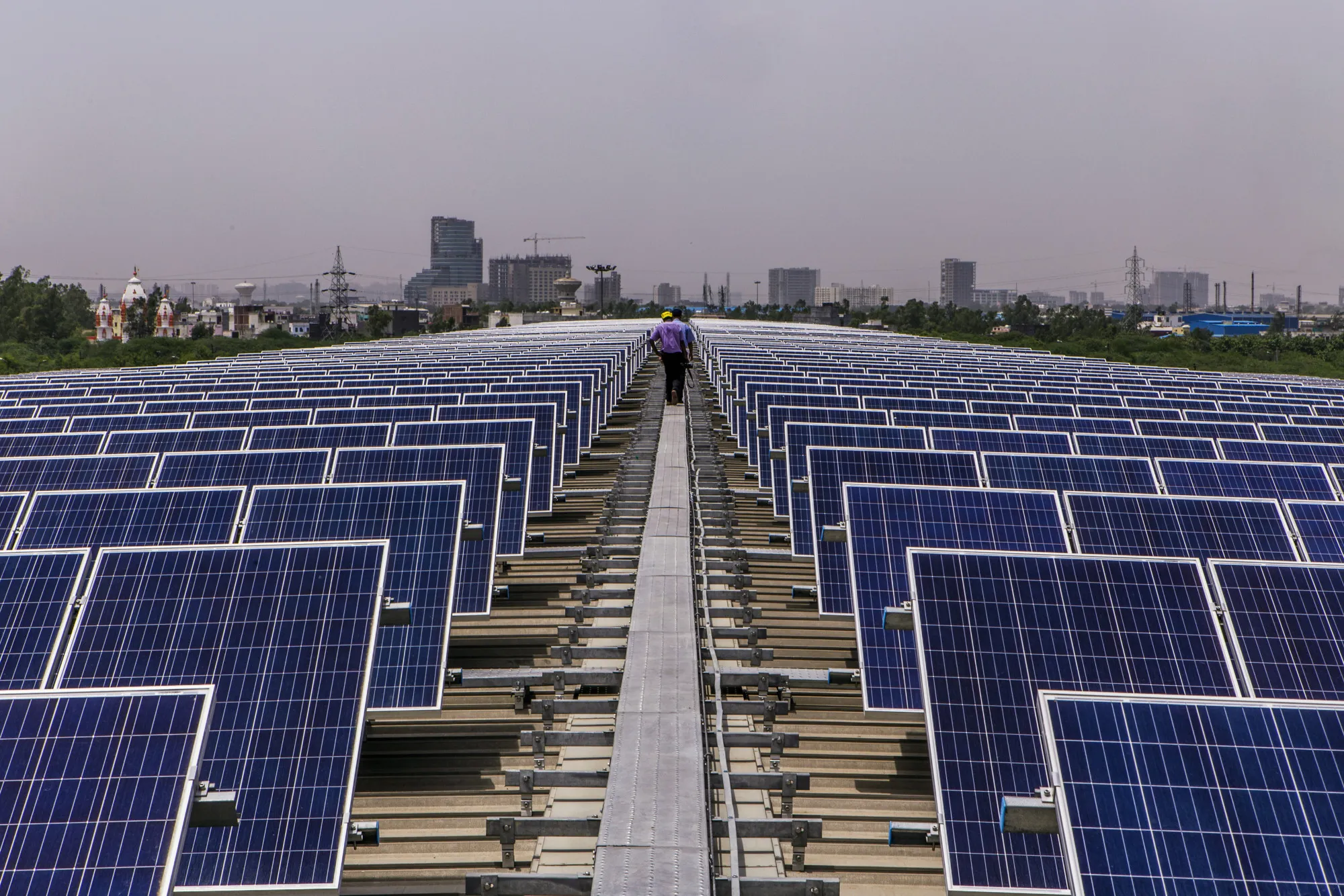 Men walk past solar panels&nbsp;in Surajpur, Uttar Pradesh, India.