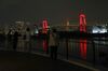 People take photographs of the Rainbow Bridge is illuminated in red on June 02, 2020 in Tokyo, Japan.