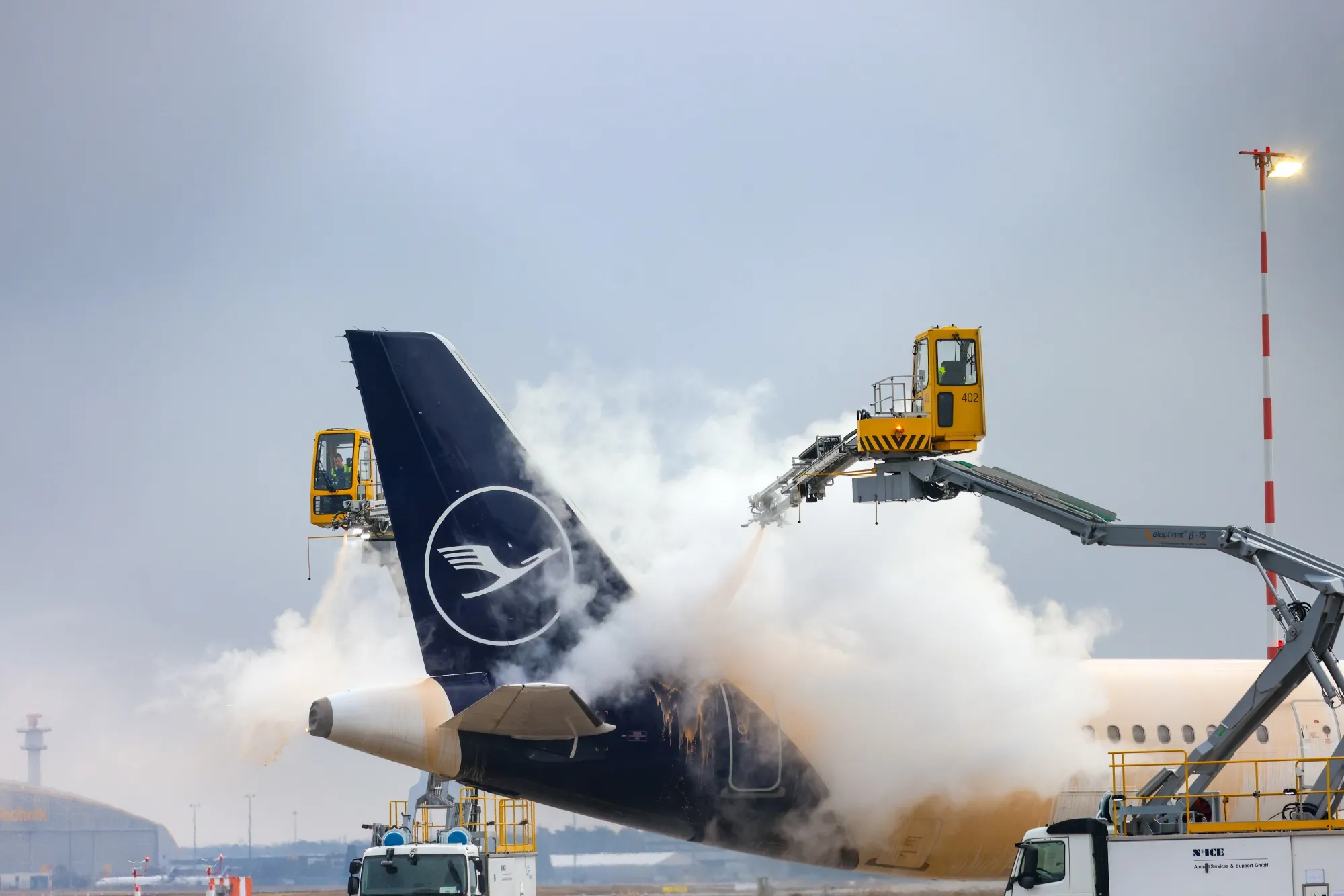 Ground crew members spray de-icing fluid onto a passenger aircraft, operated by Deutsche Lufthansa AG, at Frankfurt Airport on Jan. 30.&nbsp;