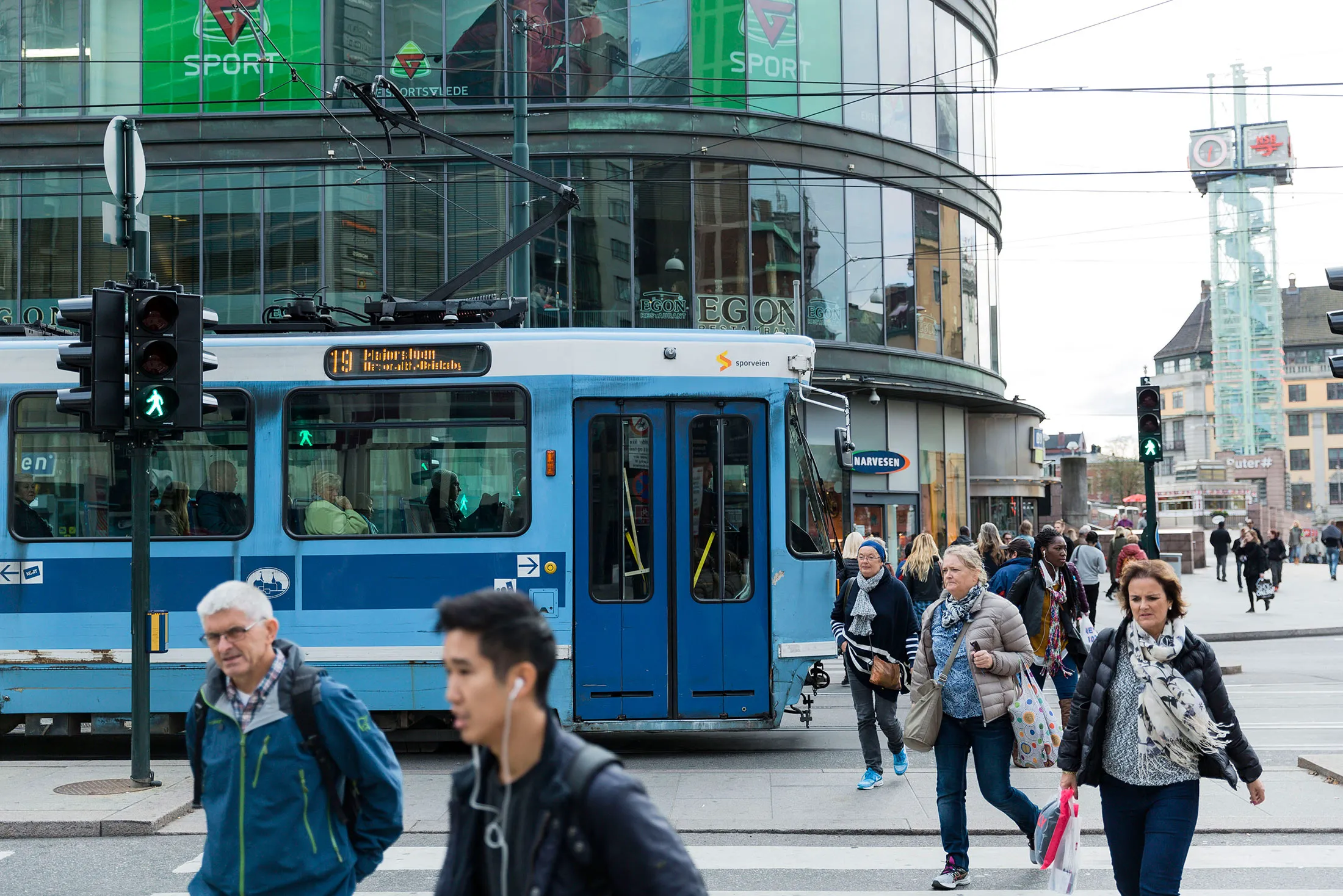 Pedestrians pass a public tram on a shopping street in central Oslo, Norway.

