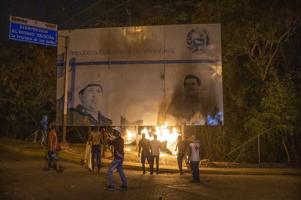 La gente incendió una cartelera con imágenes del difunto Hugo Chávez y el presidente Nicolás Maduro en el Puente Internacional Francisco De Paula Santander cerca de la frontera con Colombia en Urena, Venezuela, el 23 de febrero de 2019.