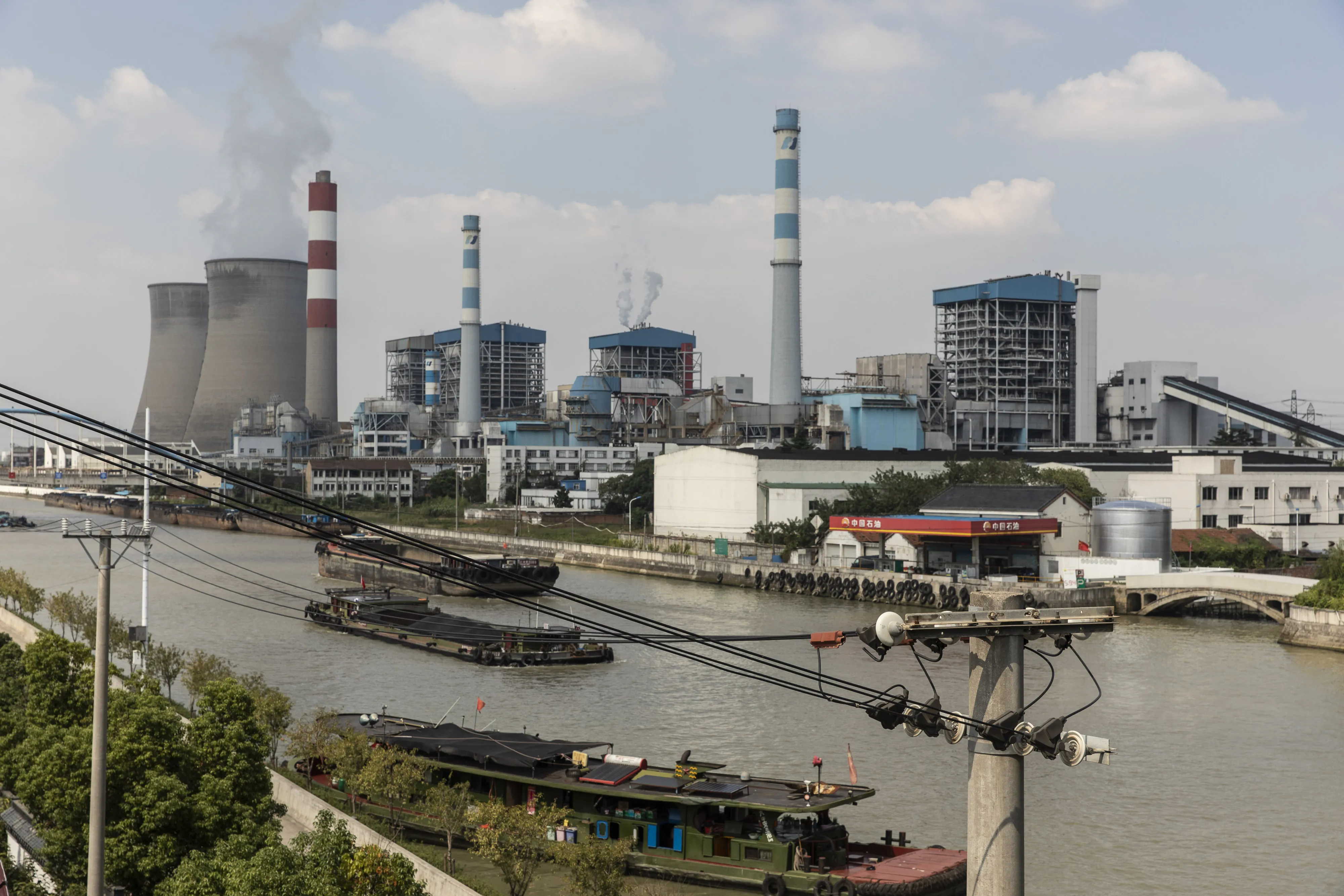 Barges travel past the Wangting Power Plant in Wangting, Jiangsu province, China