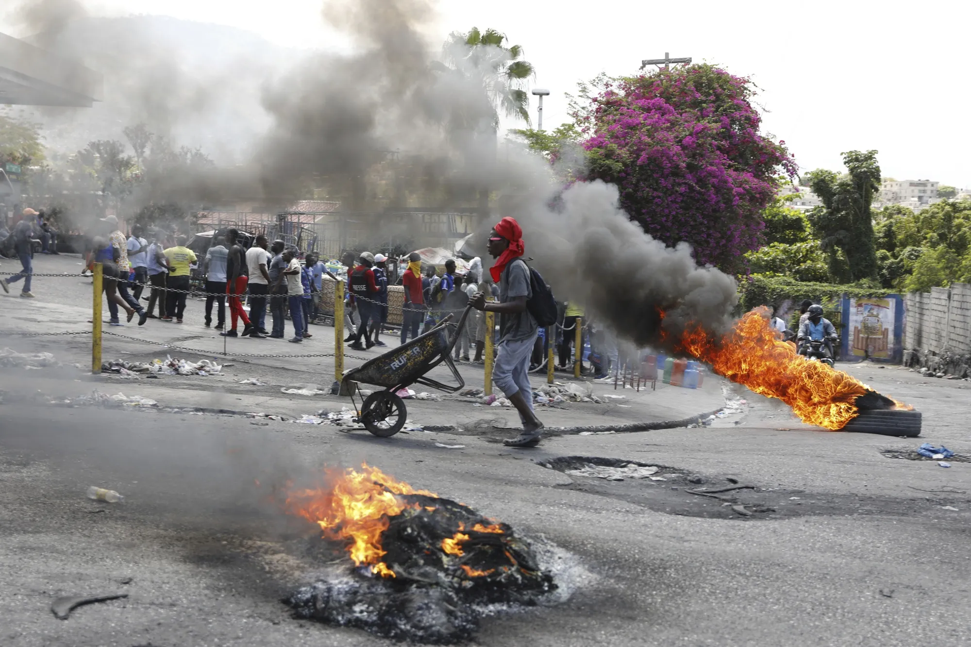 A man pushes a wheelbarrow past burning tires during a protest demanding the resignation of Prime Minister Ariel Henry&nbsp;in Port-au-Prince, Haiti on March 7.