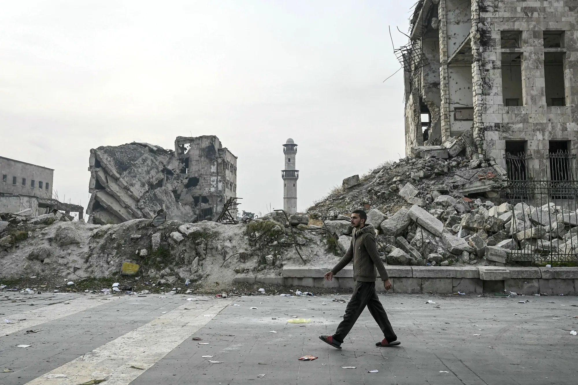 A man walks past the rubble of a damaged building at the Citadel of Aleppo in Syria, on Dec. 11.&nbsp;