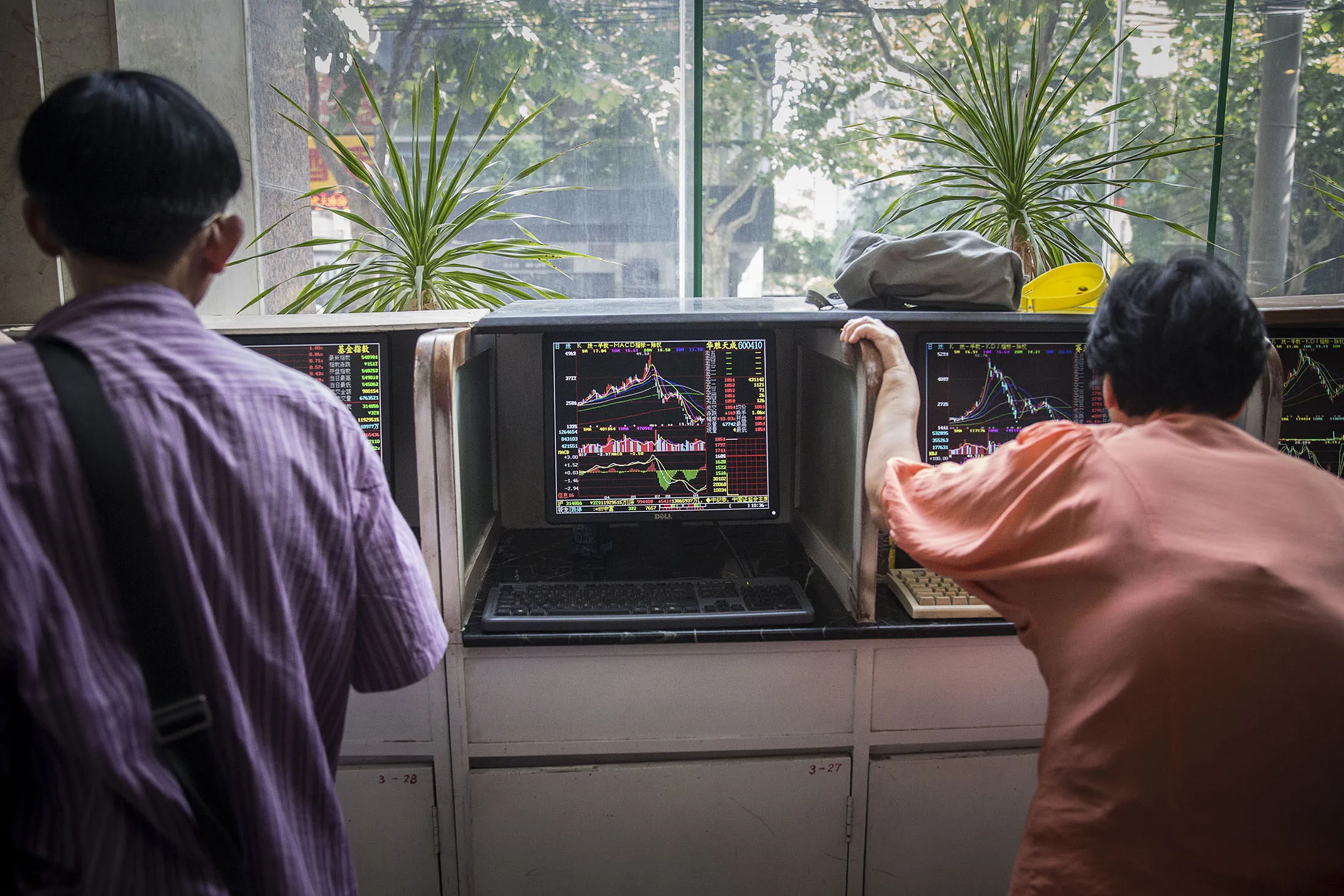Investors stand at trading terminals at a securities exchange house in Shanghai, China.
