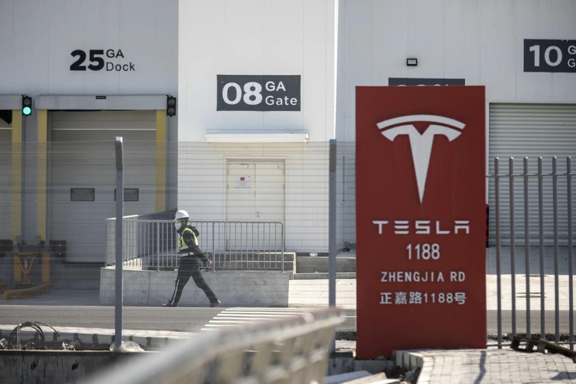 A worker walks past gates at the Tesla Inc. Gigafactory in Shanghai, China.
