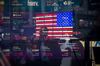 Monitors display stock market information as pedestrians are reflected in a window at the Nasdaq MarketSite in the Times Square area of New York, U.S.