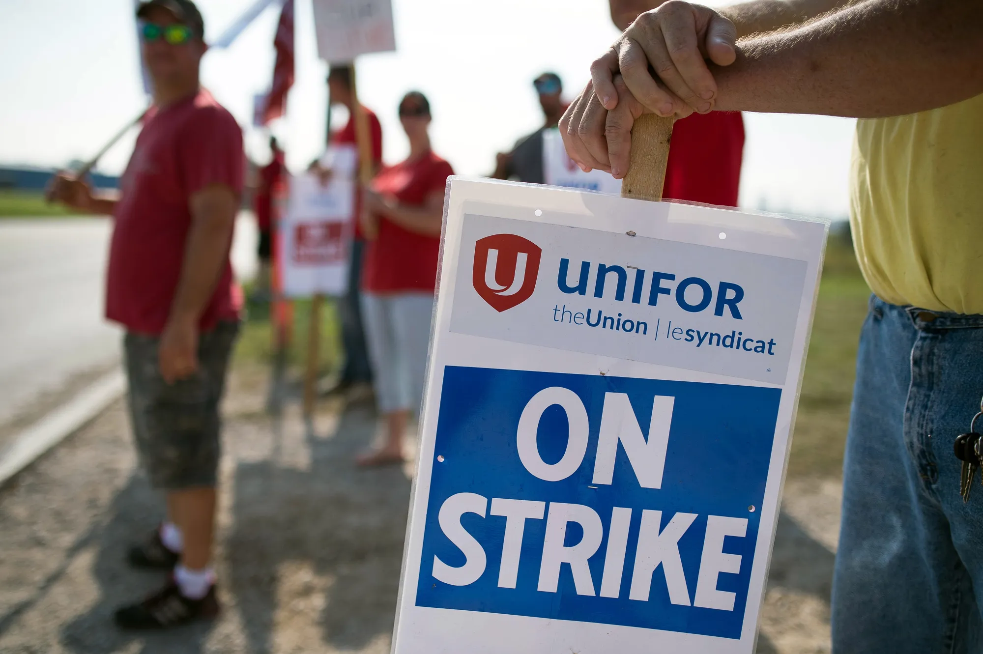Employees and Unifor members hold 'On Strike' signs outside the General Motors plant in Ingersoll, Canada, on Sept. 20, 2017.
