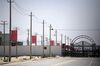 This photo taken on May 31, 2019 shows Chinese flags on a road leading to a facility believed to be a re-education camp where mostly Muslim ethnic minorities are detained, on the outskirts of Hotan in China's northwestern Xinjiang region. - As many as one million ethnic Uighurs and other mostly Muslim minorities are believed to be held in a network of internment camps in Xinjiang, but China has not given any figures and describes the facilities as "vocational education centres" aimed at steering people away from extremism. (Photo by GREG BAKER / AFP) / TO GO WITH AFP STORY CHINA-XINJIANG-MEDIA-RIGHTS-PRESS,FOCUS BY EVA XIAO (Photo credit should read GREG BAKER/AFP via Getty Images)