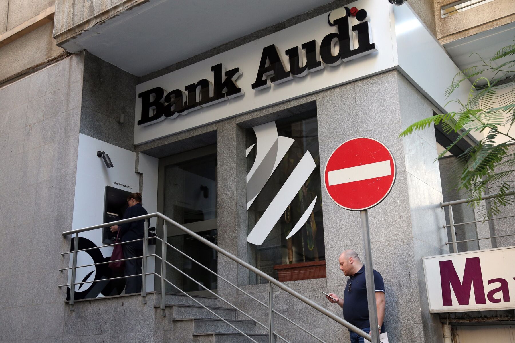Customers use an automated teller machine (ATM) outside an Audi Bank SAL bank branch in Beirut, Lebanon. 