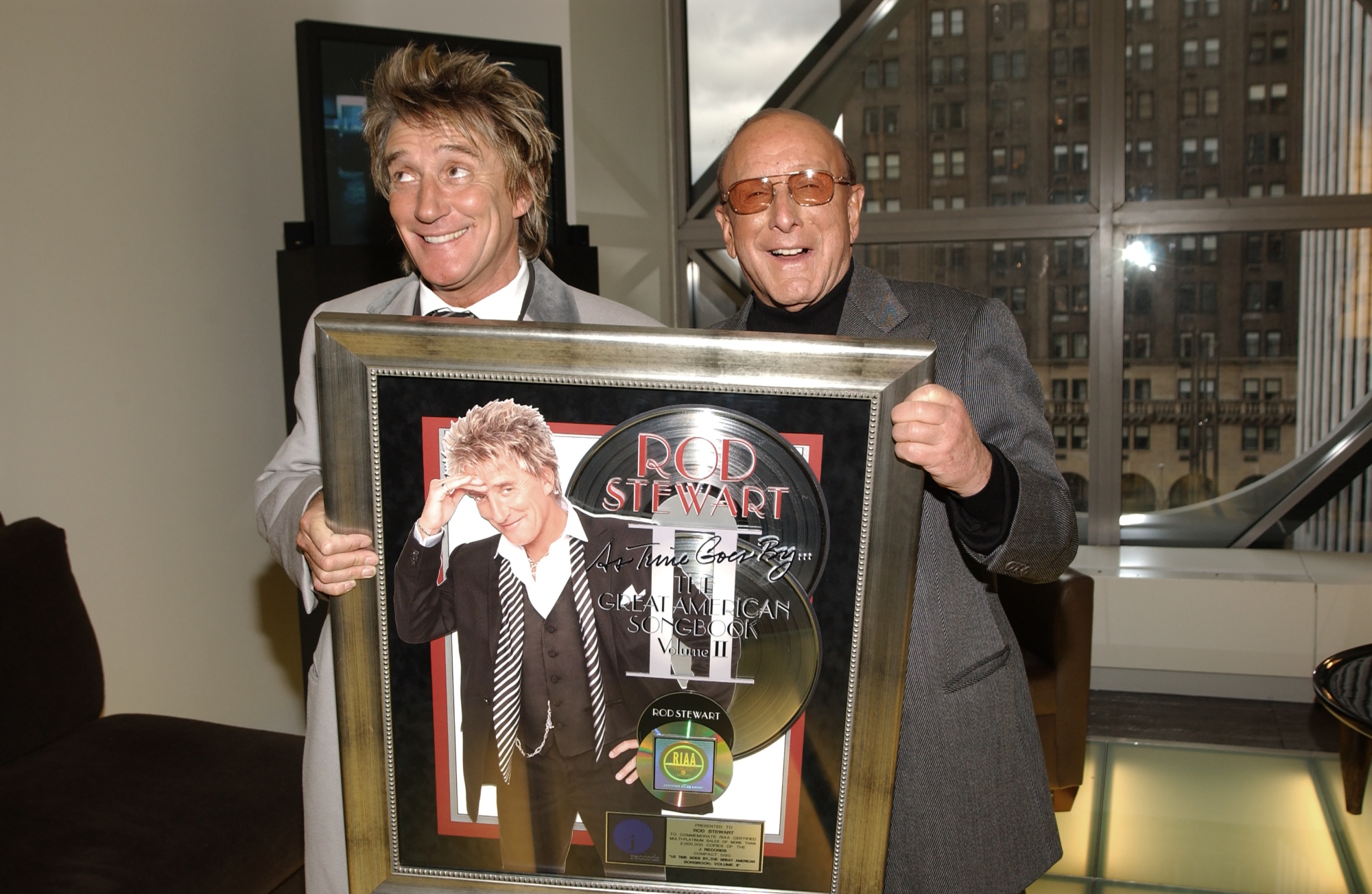 English musician Rod Stewart (left) and J Records founder &amp;amp; CEO Clive Davis pose together with a platinum record at the J Records offices, New York, New York, December 11, 2003. Photographer: Gary Gershoff