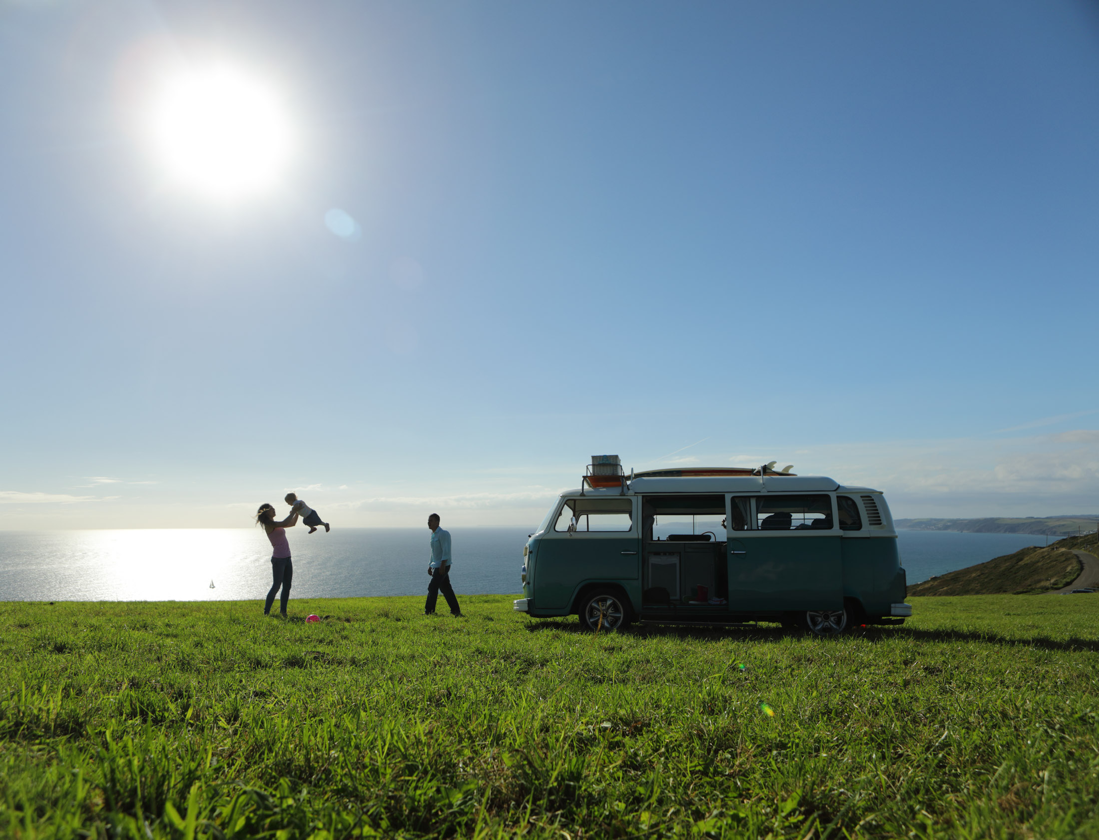 Family with camper in field by sea
