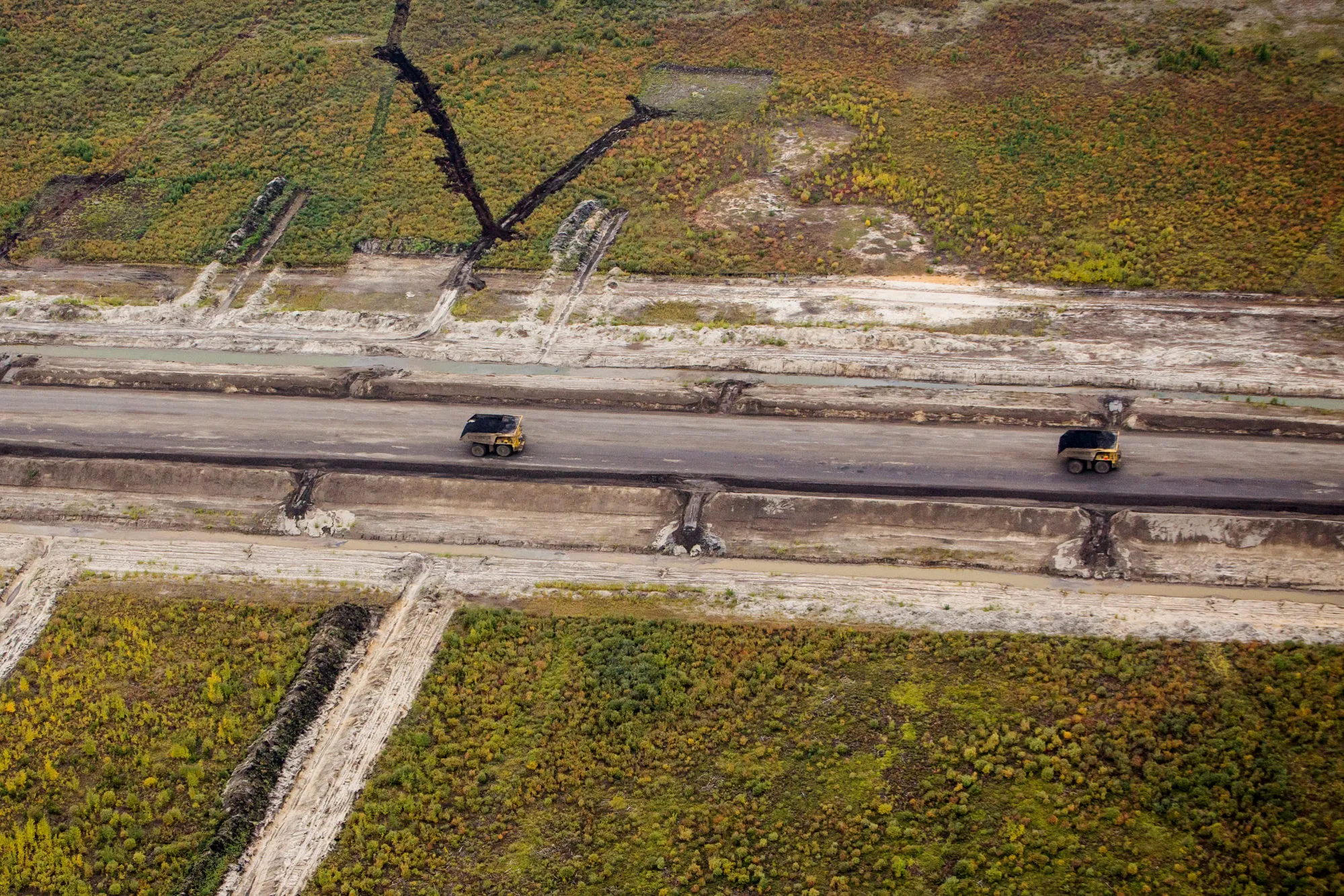 Heavy haulers drive through a mine in this aerial photograph taken above the Athabasca oil sands, near Fort McMurray, Alberta, in September 2018.