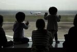 Children watch an All Nippon Airways Co. (ANA) aircraft taking off at Haneda Airport in Tokyo, Japan.