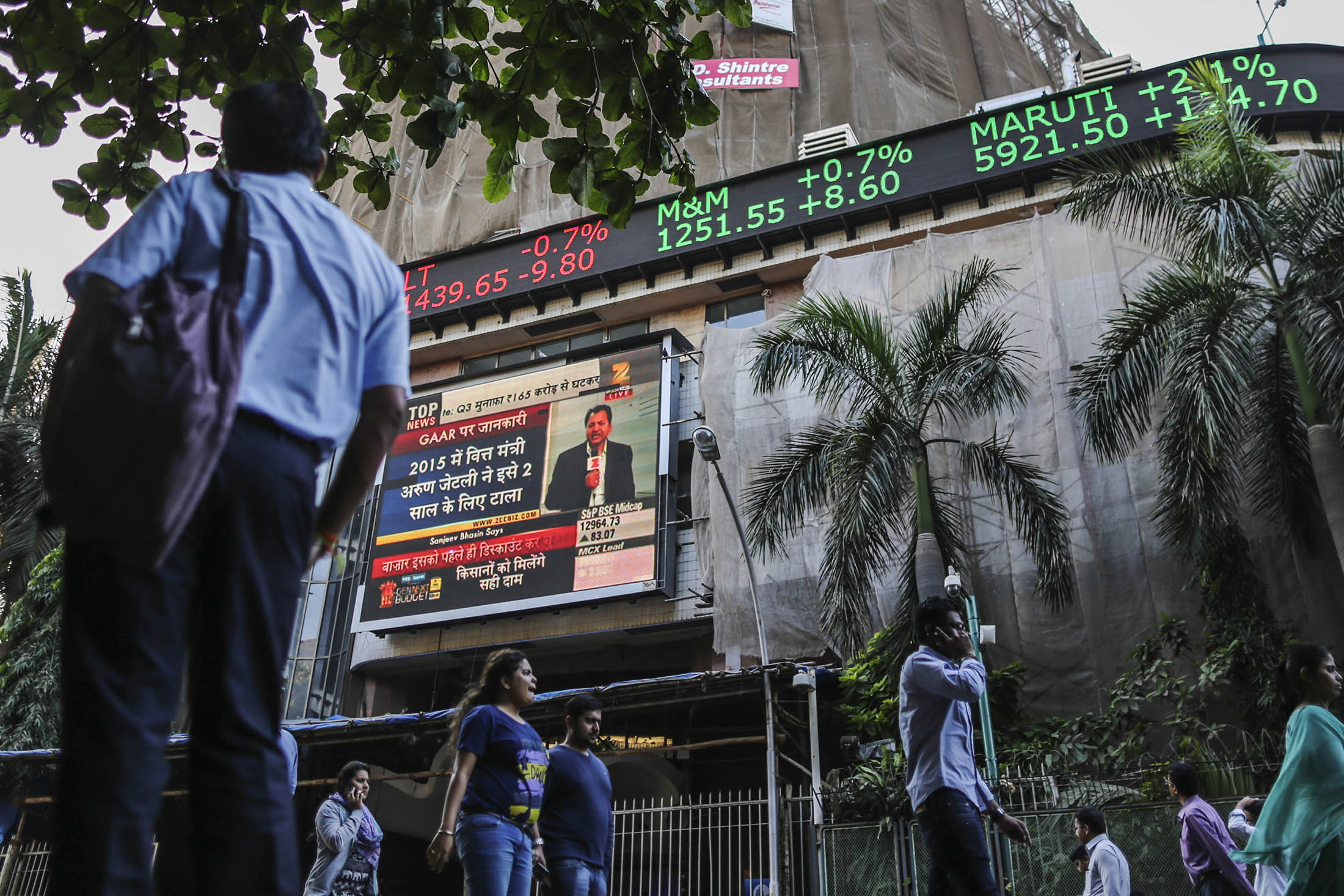 A man looks up at an electronic ticker board that indicates stock figures at the Bombay Stock Exchange in Mumbai
