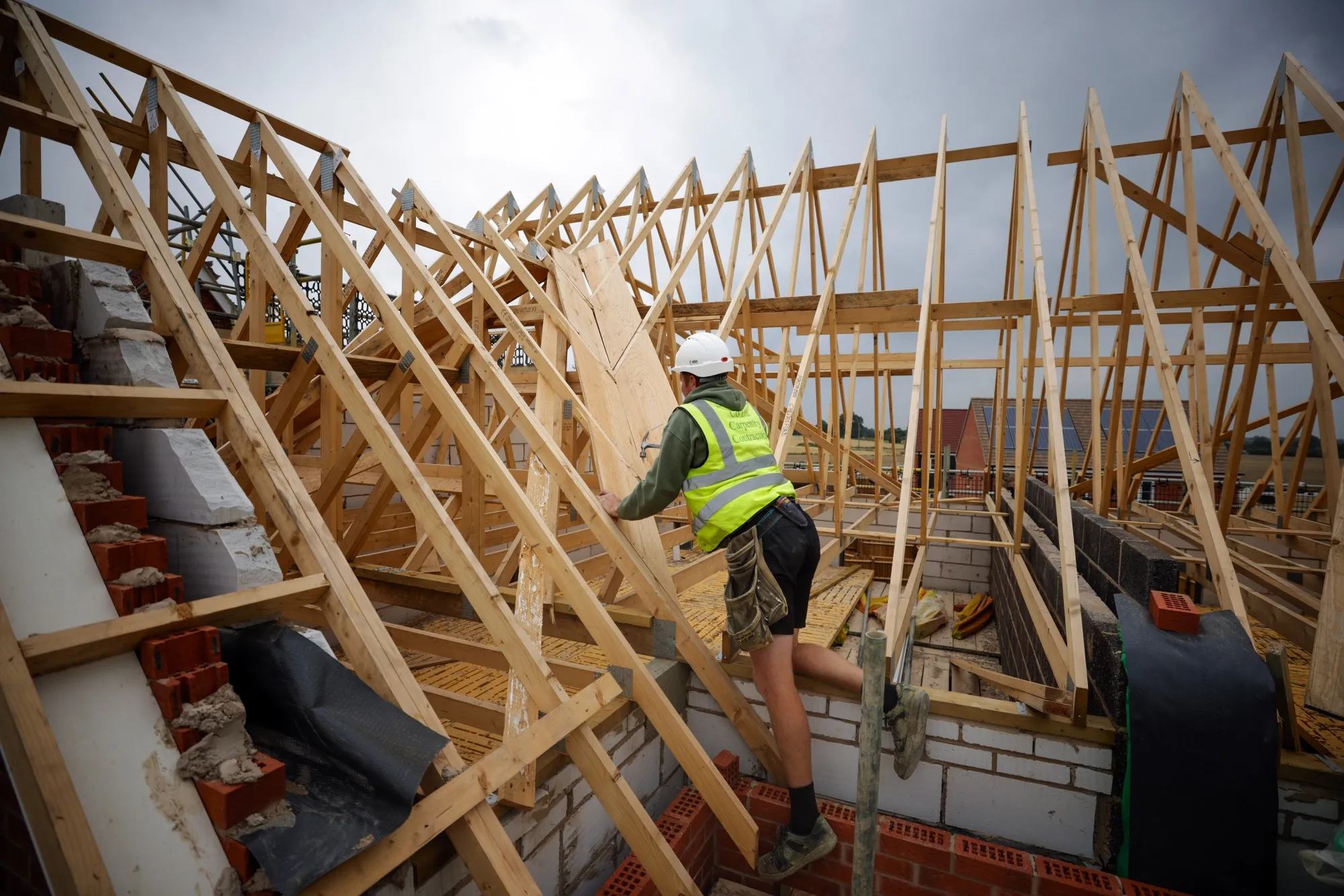 A worker constructs a timber roof for a house on a residential property construction site in Chelmsford, U.K.