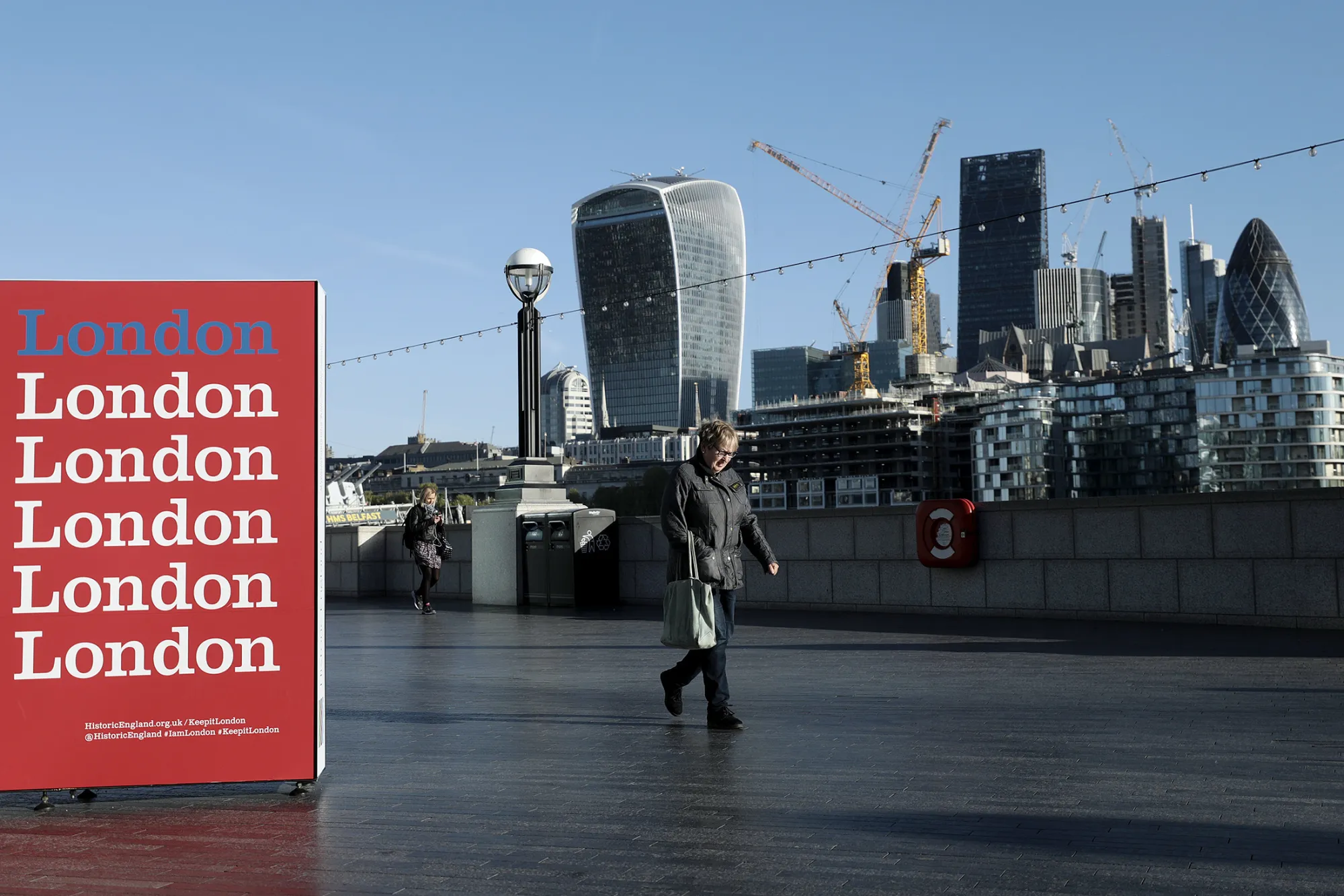 A pedestrian passes by as skyscrapers including Tower 42, the Heron Tower, the Leadenhall building, also known as the 'Cheesegrater,' 30 St Mary Axe, also known as 'the Gherkin,' and 20 Fenchurch Street, also known as the 'Walkie-Talkie,' stand beyond, in London, U.K., on Tuesday, April 18, 2017. Global banks have started arranging for some British-based operations to move to new or expanded offices inside the EU after British Prime Minister Theresa May triggered discussions to leave the trading bloc.
