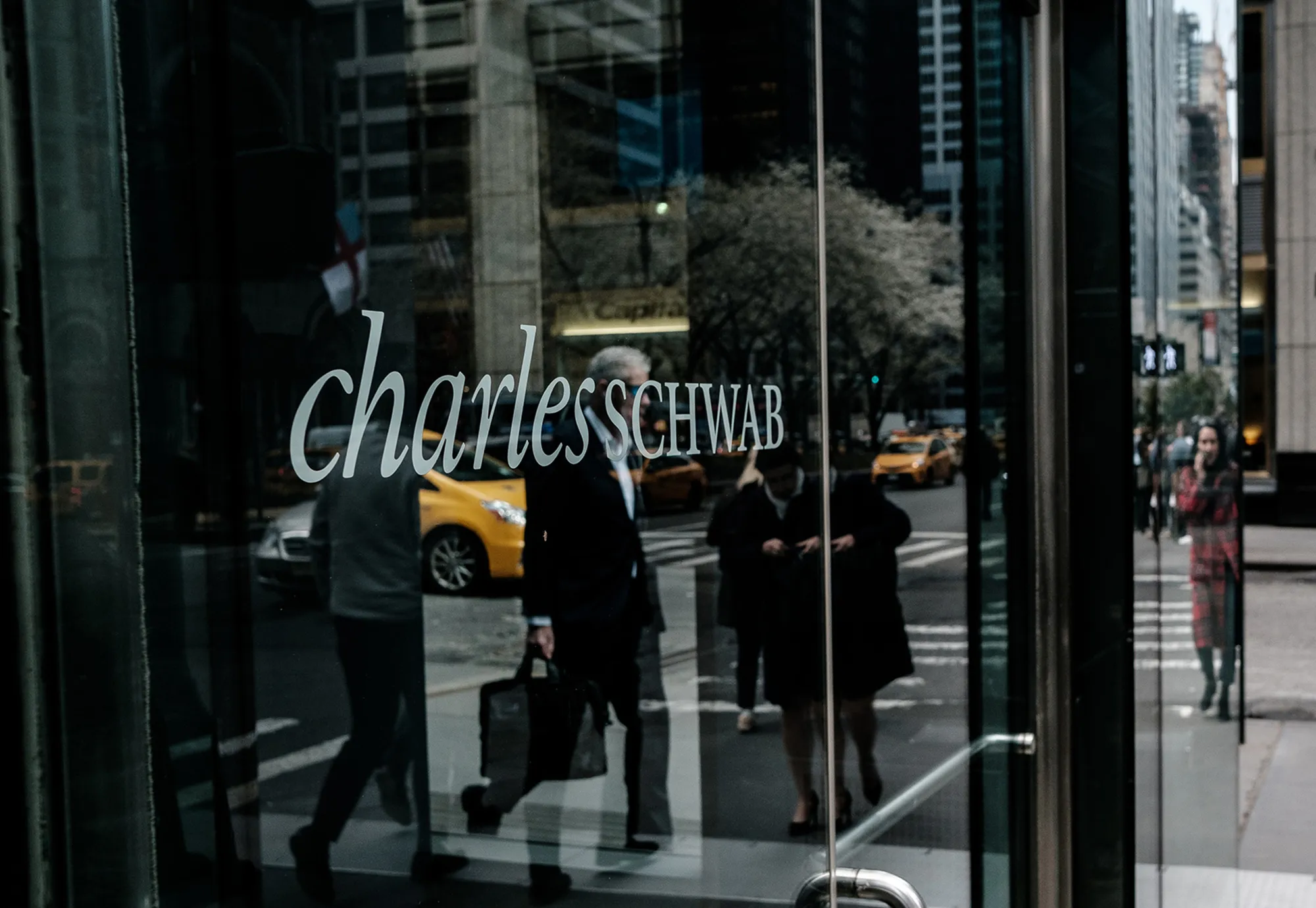 Pedestrians pass in front of a Charles Schwab Corp. office building in New York.