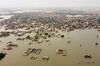 An aerial view of a flooded residential area in a city in Pakistan, with muddy waters fully covering any street between the habitations.