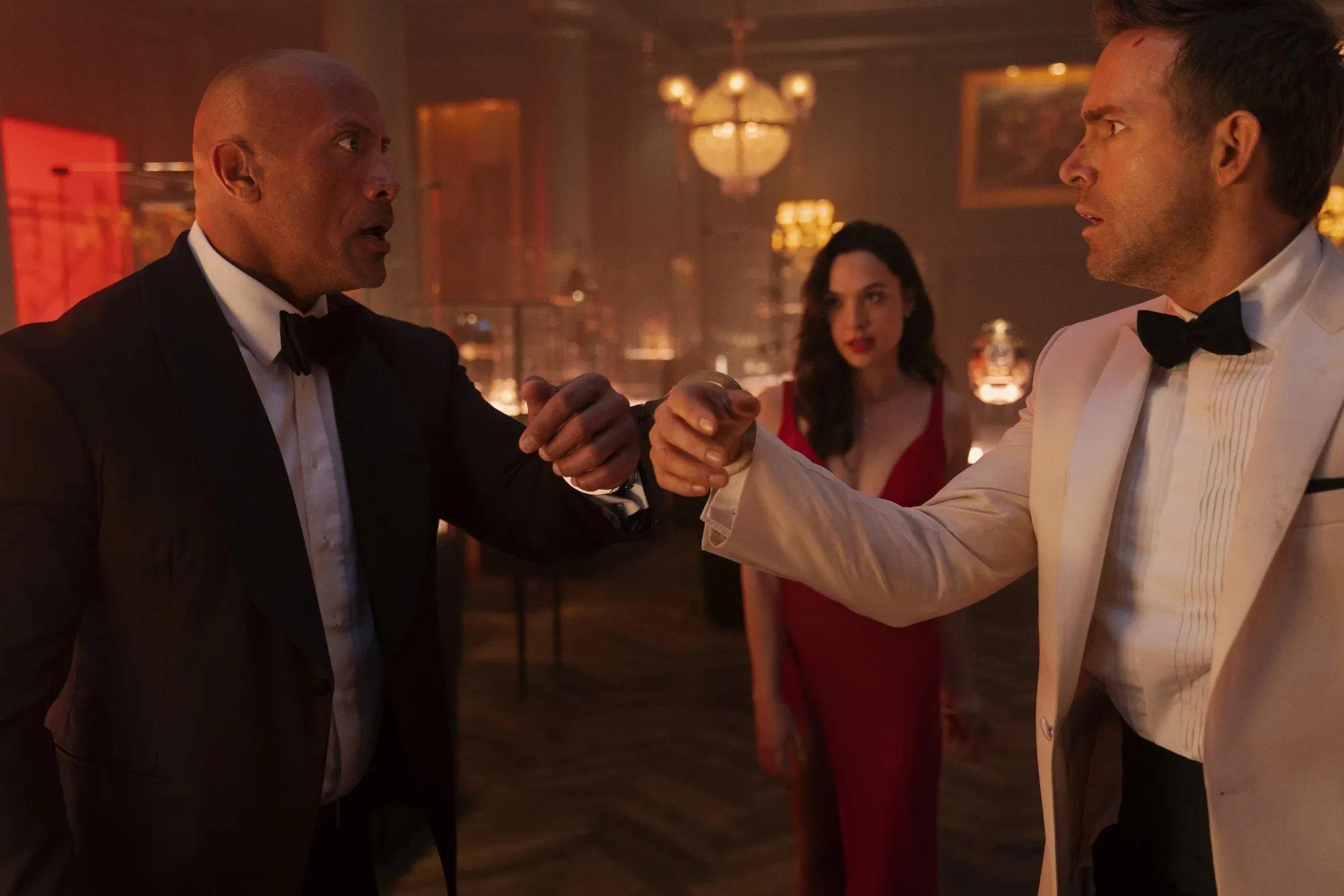 RED NOTICE - (L-R) Dwayne Johnson is the FBI’s top profiler John Hartley, Gal Gadot is the world’s most wanted art thief “The Bishop” and Ryan Reynolds is the world’s greatest art thief Nolan Booth in Netflix's RED NOTICE. Directed and written by Rawson Marshall Thurber, RED NOTICE is releasing November 12, 2021. Cr: Frank Masi / Netflix © 2021