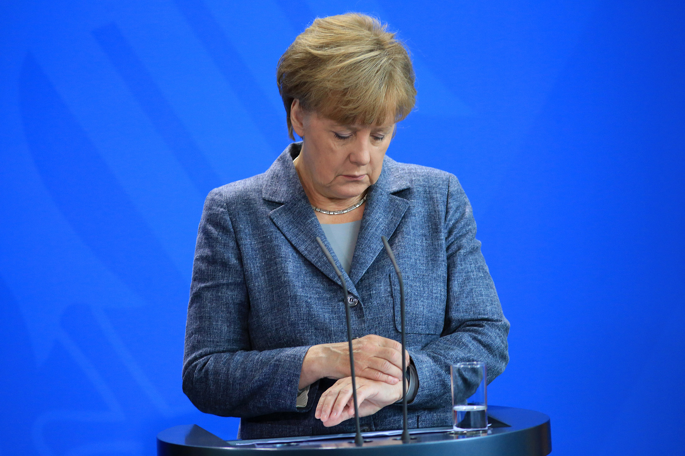 Angela Merkel, Germany's chancellor, looks at her wristwatch during a news conference at the Chancellery in Berlin, Germany, on Monday, Sept. 7, 2015.

